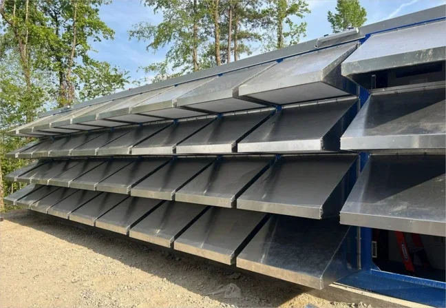 Rows of angled metal hoods covering the air intakes along the side of a mining container